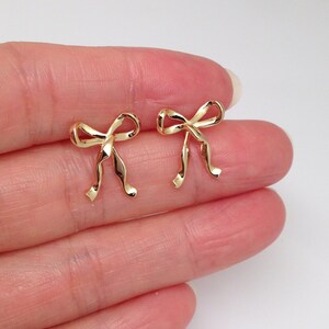 Puede incluir: Un par de pendientes de bot&oacute;n de oro en forma de lazo. Los pendientes son peque&ntilde;os y delicados, y ser&iacute;an un gran regalo para una ocasi&oacute;n especial.