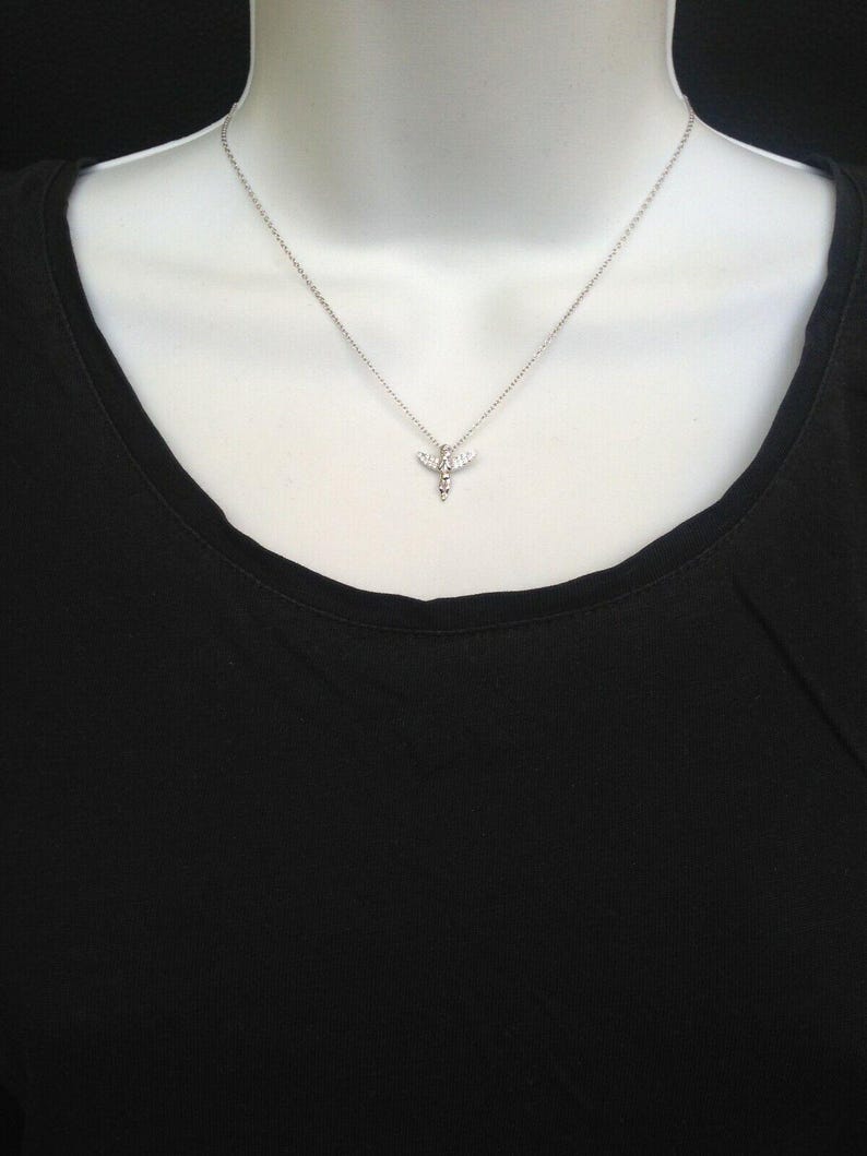 Puede incluir: Un collar de cadena de plata con un peque&ntilde;o colgante de lib&eacute;lula de cristal transparente.