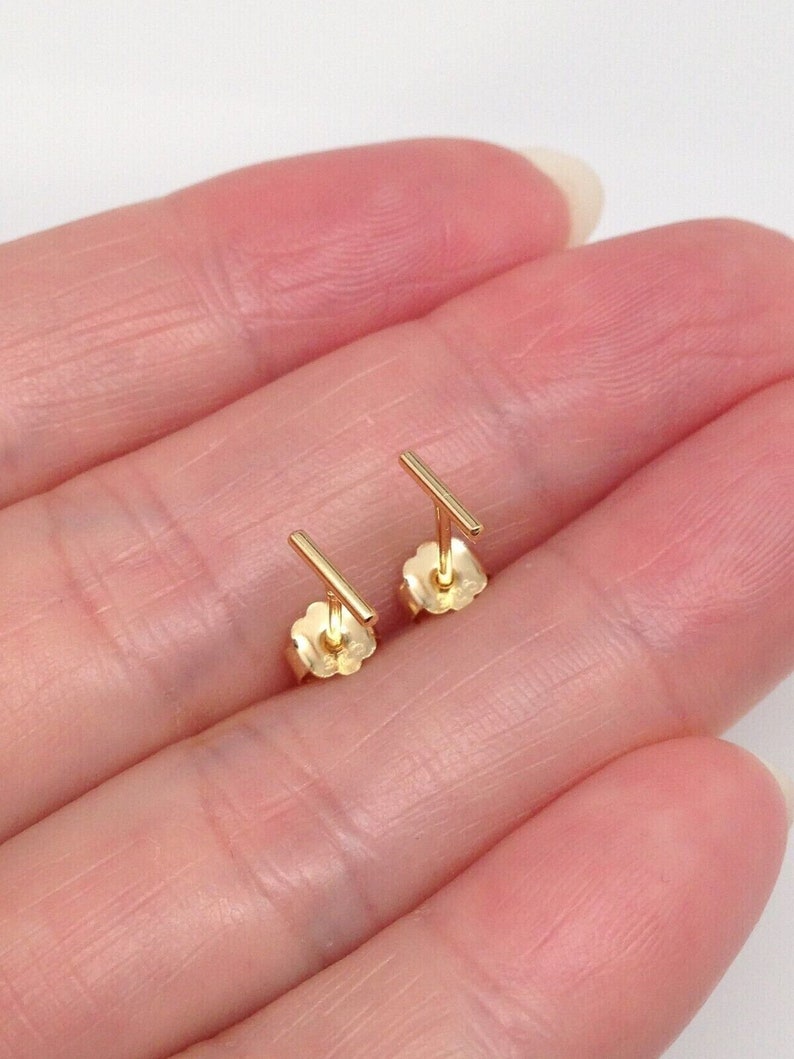 K&ouml;nnte beinhalten: Ein Paar goldene Bar-Ohrstecker. Die Ohrringe sind schlicht und minimalistisch, mit einem geraden Barren-Design.