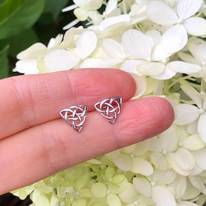 May include: A pair of silver Celtic knot triangle stud earrings. The earrings are small and delicate, and they are perfect for everyday wear.