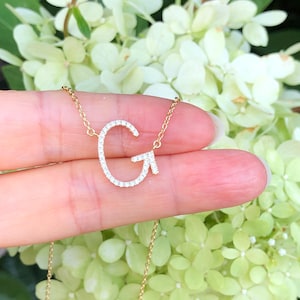 May include: A gold chain necklace with a diamond-encrusted letter G pendant.