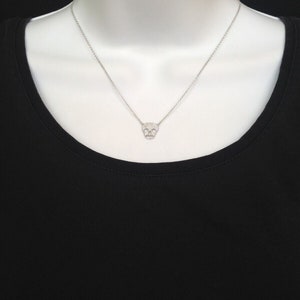 Puede incluir: Un collar de cadena de plata con un peque&ntilde;o colgante de calavera pav&eacute;.