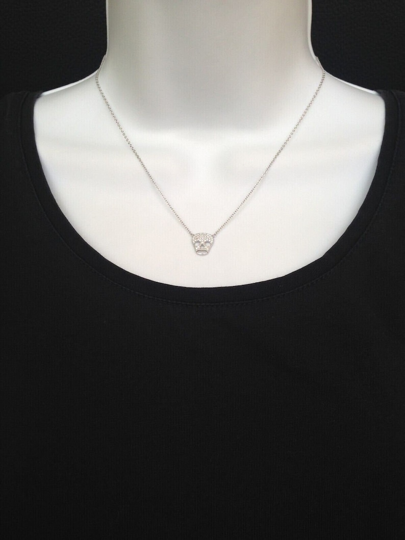 Puede incluir: Un collar de cadena de plata con un peque&ntilde;o colgante de calavera pav&eacute;.
