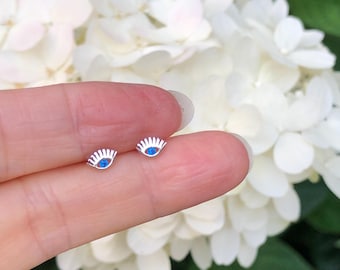 May include: A pair of silver earrings with a blue eye design. The earrings are small and delicate, and they would make a great gift for someone who loves unique jewelry.