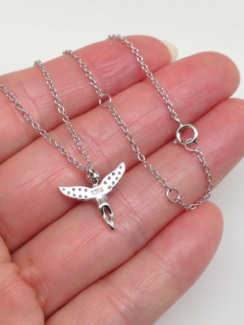 Puede incluir: Un collar de cadena de plata con un peque&ntilde;o colgante de &aacute;ngel. El &aacute;ngel tiene alas con peque&ntilde;as piedras transparentes y un halo. La cadena es una cadena de cable delicada.