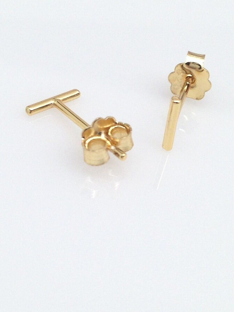 K&ouml;nnte beinhalten: Ein Paar goldfarbene Bar-Ohrstecker. Die Ohrringe sind schlicht und minimalistisch, mit einem geraden Barren-Design.