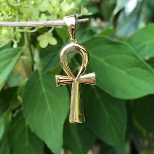 May include: A gold-colored Ankh pendant, a symbol of eternal life in ancient Egyptian mythology.