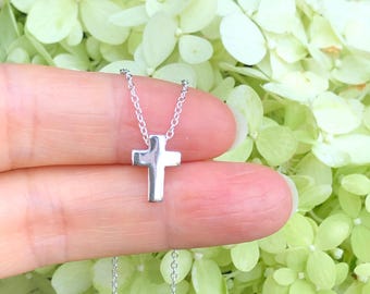 May include: A silver chain necklace with a small, simple silver cross pendant.
