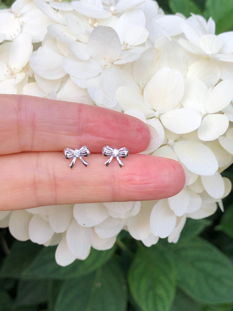 May include: A pair of silver bow-shaped stud earrings.