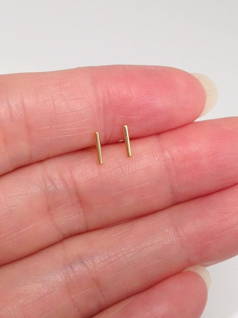 K&ouml;nnte beinhalten: Ein Paar goldene Barren-Ohrstecker. Die Ohrringe sind klein und schlicht, was sie zu einer guten Wahl f&uuml;r den Alltag macht.