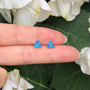 May include: A pair of gold triangle earrings with three blue opal stones in each earring.