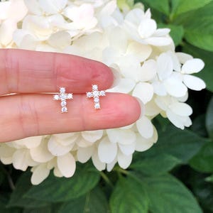 May include: A pair of small, silver cross earrings with clear cubic zirconia stones.