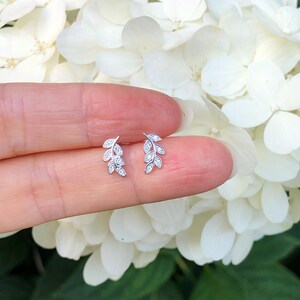 May include: A pair of silver leaf earrings with small clear cubic zirconia stones. The earrings are delicate and feminine.