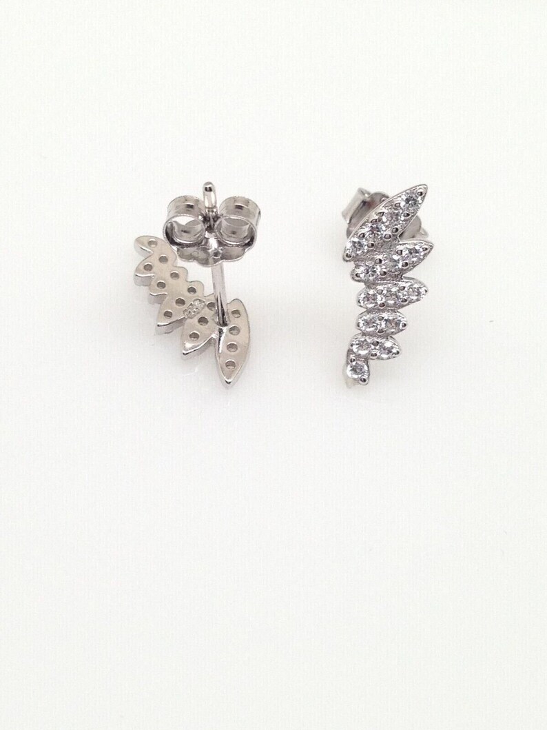 May include: A pair of silver earrings with a leaf design. Each earring has a row of small, clear stones that form the shape of a leaf.