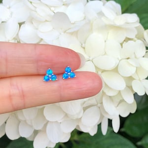 May include: A pair of silver stud earrings with three blue opal stones each.