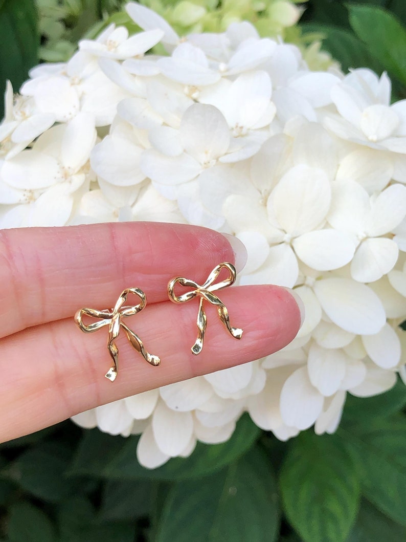 Puede incluir: Un par de pendientes de oro en forma de lazo. Los pendientes son peque&ntilde;os y delicados, y son perfectos para a&ntilde;adir un toque de elegancia a cualquier atuendo.