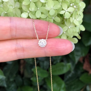Peut inclure: Un collier délicat en chaîne dorée avec un petit pendentif rond orné d'un groupe de diamants étincelants.