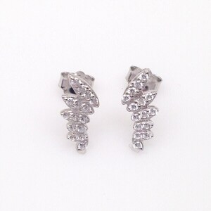 May include: A pair of silver earrings with a cascading design of small, clear cubic zirconia stones.