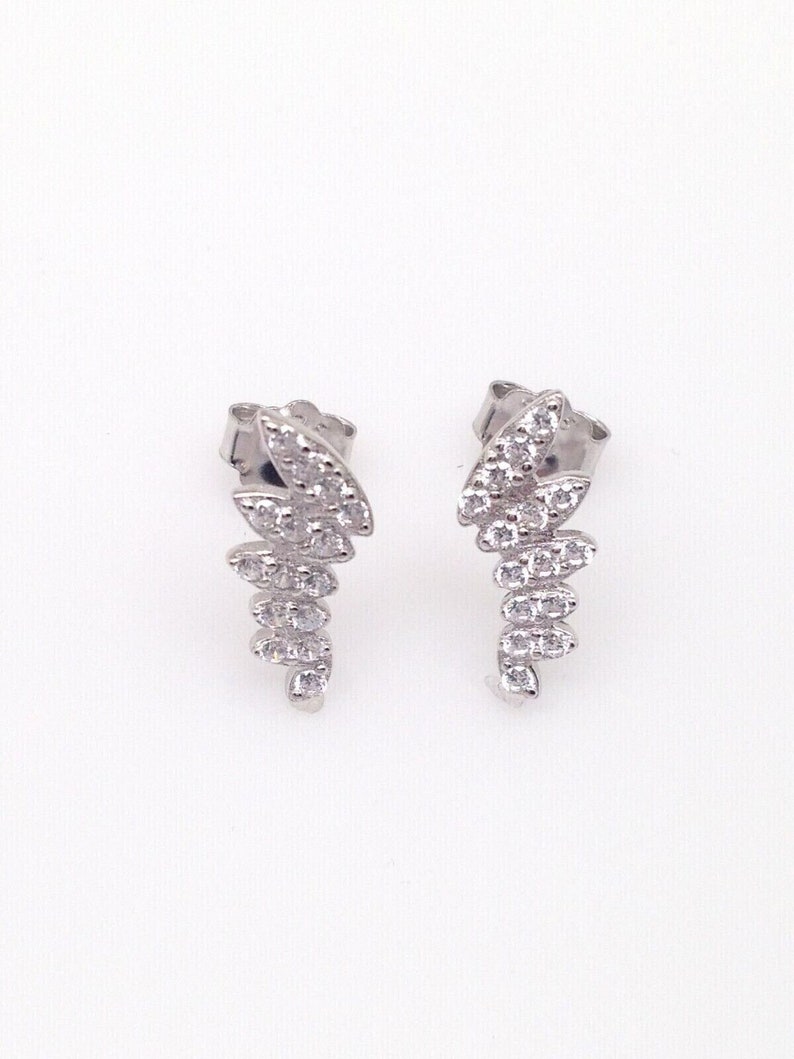 May include: A pair of silver earrings with a cascading design of small, clear cubic zirconia stones.
