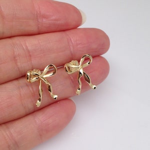 Puede incluir: Un par de pendientes de lazo de color dorado. Los lazos est&aacute;n retorcidos y tienen un aspecto delicado y femenino.