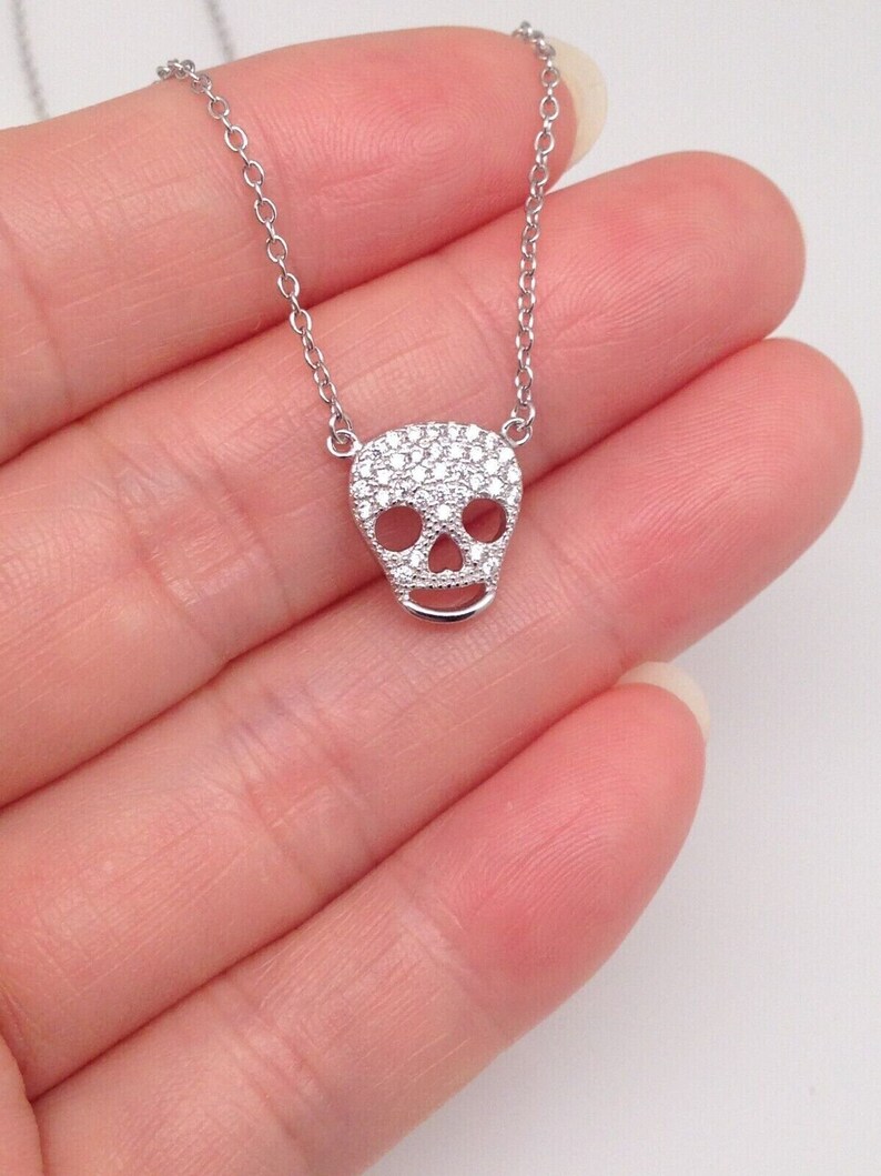Puede incluir: Un collar de cadena de plata con un peque&ntilde;o colgante de calavera incrustado con circonitas c&uacute;bicas.