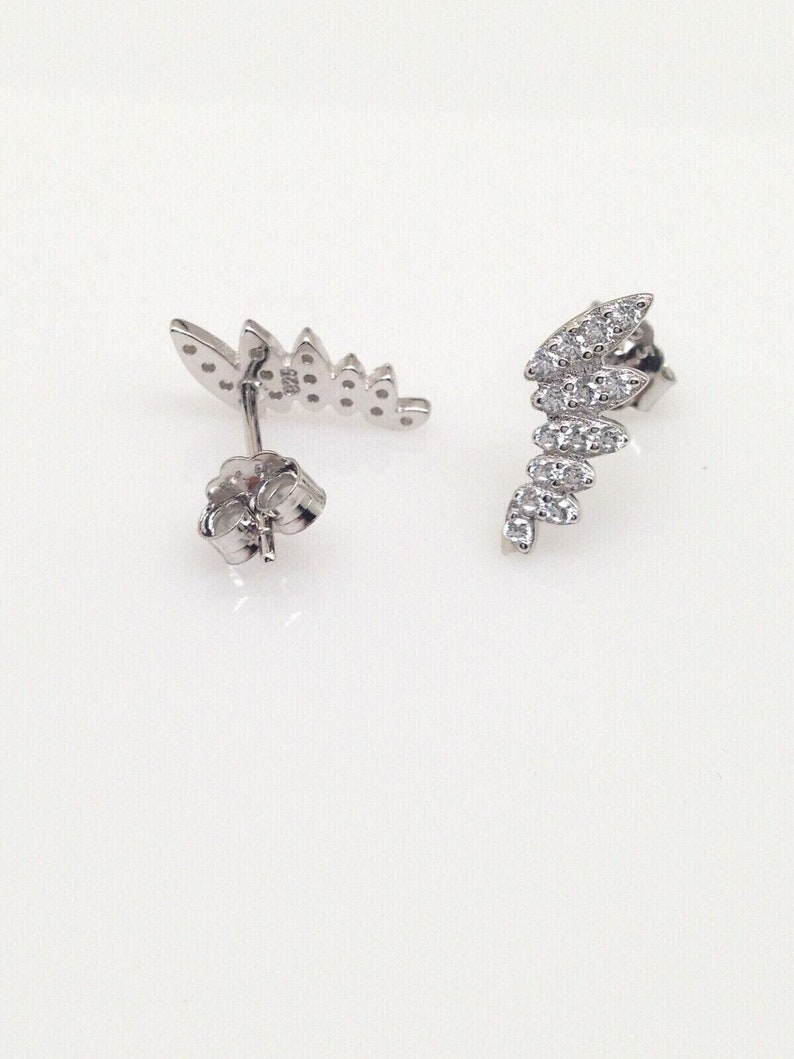 May include: A pair of silver earrings with a leaf design. The earrings are adorned with small, clear stones.