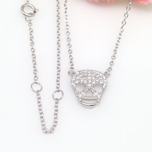 Puede incluir: Un collar de cadena de plata con un peque&ntilde;o colgante de calavera pav&eacute;. El colgante est&aacute; hecho de plata y est&aacute; cubierto de peque&ntilde;as piedras de circonita c&uacute;bica transparentes.
