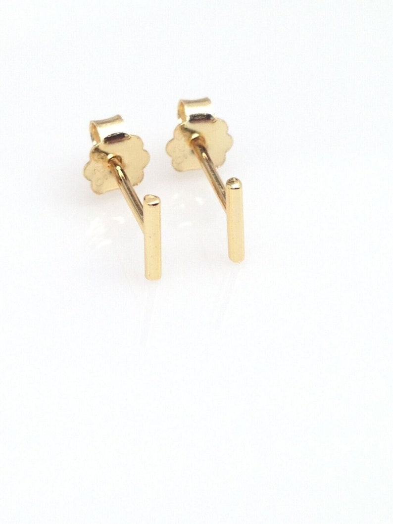 K&ouml;nnte beinhalten: Ein Paar goldene Bar-Ohrstecker. Die Ohrringe sind schlicht und minimalistisch, mit einem geraden Barren-Design.