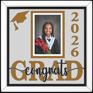 May include: A framed graduation photo with a smiling graduate holding red roses. The frame includes the word "Congrats" and "GRAD" in gold, along with the year "2026" in gold. A gold graduation cap is in the upper left corner.