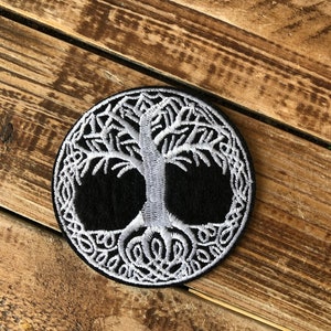 May include: White embroidered tree of life patch on a black background. The patch is circular and has a Celtic knot border.