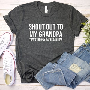 Może przedstawiać: Szary t-shirt z białym napisem "Shout out to my grandpa that's the only way he can hear".