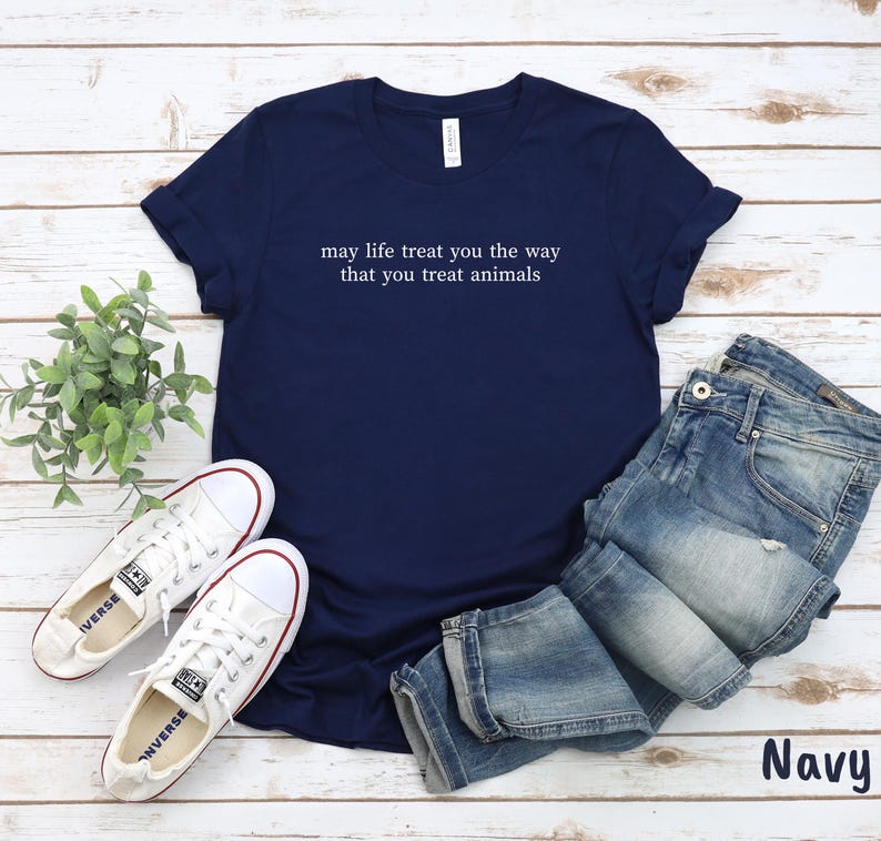 May include: Navy blue t-shirt with white text: "may life treat you the way that you treat animals". The image includes blue jeans and white trainers. The word "Navy" is visible in the bottom right corner.