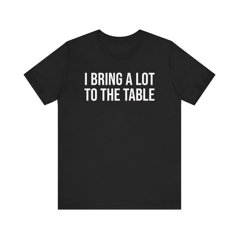 Może przedstawiać: Czarny T-shirt z białym napisem "Wnoszę wiele do stołu."