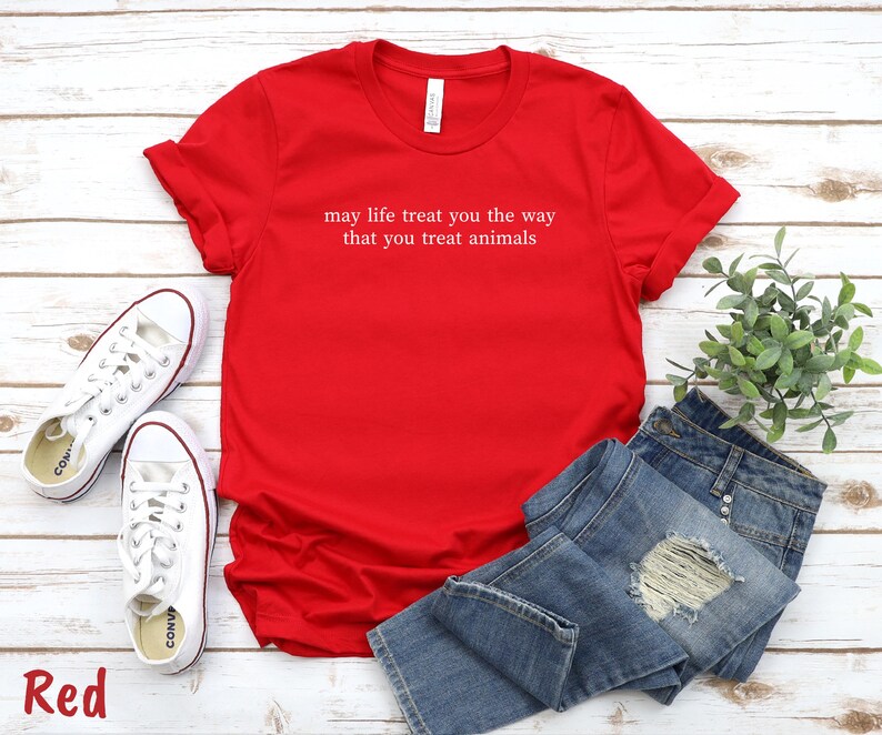 May include: A bright red t-shirt with the white text "may life treat you the way that you treat animals". The image also shows blue denim jeans and white trainers. The word "Red" is in the bottom left corner.