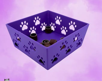 May include: A square purple plastic storage bin featuring cut-out paw print designs on all four sides. The interior of the container holds several small, cylindrical brown sanding bands. The text GHOSTLAYER is printed in the bottom left corner.
