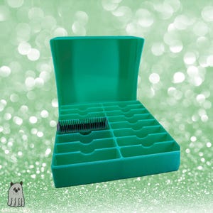 Könnte beinhalten: Eine türkisgrüne Aufbewahrungsbox mit mehreren Fächern, ideal zum Organisieren kleiner Gegenstände. Die Box ist geöffnet und zeigt die Innenaufteilung. Ein schwarzes und silbernes Objekt befindet sich in einem der Fächer. Der Hintergrund ist ein weiches, verschwommenes Grün.