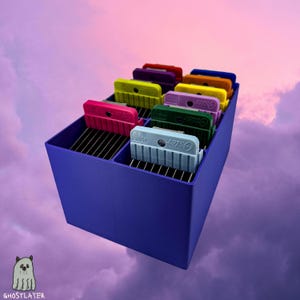 May include: A purple storage container filled with colorful Oster clipper guides. The guides are in various colors, including pink, yellow, green, and blue. The container has a divided interior and sits against a cloudy sky background.
