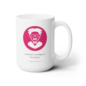 May include: White ceramic mug with a pink circle featuring a white silhouette of Albert Einstein. The quote "Creativity is intelligence having fun." is printed below the image, with "ALBERT EINSTEIN" printed below the quote.