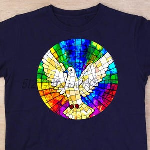 May include: Navy blue t-shirt featuring a colorful stained-glass design of a dove with outstretched wings. The dove is white and yellow, set against a vibrant rainbow background. The shirt is a classic crew neck style.
