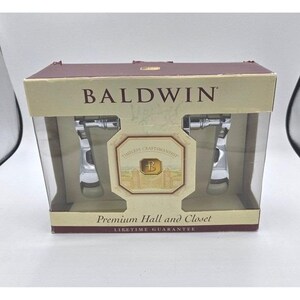 May include: A box of Baldwin hall and closet hardware. The box is brown and clear, with the brand name and "Timeless Craftsmanship" printed on it. The box contains two chrome-coloured handles.