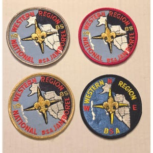 Puede incluir: Cuatro parches bordados con el texto "Western Region National BSA Jamboree 85". Cada parche presenta una rosa de los vientos y un contorno de mapa, con bordes de diferentes colores: plateado, rojo, dorado y azul marino.