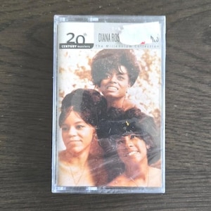 Puede incluir: Un casete vintage con Diana Ross y The Supremes. La portada del álbum muestra a tres mujeres en primer plano. La caja del casete tiene el texto "20th Century Masters" y "The Millennium Collection".