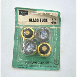 May include: Vintage package of four glass fuses, labeled "GLASS FUSE" and "15 AMP FUSE." The package is green and white, with the Sears logo. Each fuse is encased in a clear plastic with gold and black accents.
