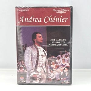 May include: A DVD case for the opera Andrea Chénier by Giordano, performed at Teatro alla Scala. The cover features a person in a light-colored patterned coat, with the names José Carreras, Eva Marton, and Piero Cappuccilli printed in white.
