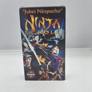 May include: A VHS tape for the animated film "Ninja Scroll" featuring a dynamic illustration of characters with swords. The box has the title in gold lettering and the Manga Entertainment logo.