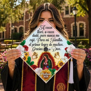 Op de afbeelding: Een afstudeerhoed met decoraties, Spaanse tekst, bloemmotieven en vlinders. De hoed toont een afbeelding van de Maagd Maria, de naam "Madison" en het jaar "2026". De hoed is versierd met een kwast.