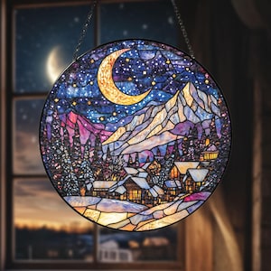 May include: Round stained glass window art depicting a winter mountain scene under a starry night sky with a crescent moon. The artwork features a village, snow-covered mountains, and evergreen trees, with a black metal frame and hanging chain.