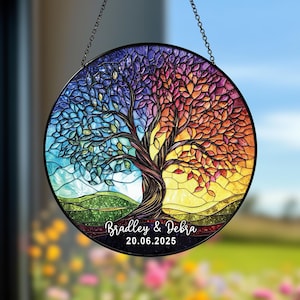 Può includere: Vetrata rotonda con un disegno ad albero. L'albero è diviso in due metà, una in blu e verdi freddi, l'altra in arancioni e gialli caldi. I nomi "Bradley & Debra" e la data "20.06.2025" sono in basso.