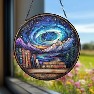 Könnte beinhalten: Ein hängendes Buntglasfenster mit einem runden Design, das einen Nachthimmel mit einer wirbelnden Galaxie, Bergen, einem See und einem Bücherregal zeigt. Das Fenster ist mit schwarzem Metall gerahmt.