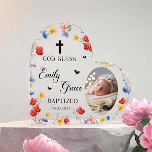 Może przedstawiać: Akrylowa ramka na zdjęcia w kształcie serca z kwiatowymi akcentami. Ramka zawiera napis "GOD BLESS Emily Grace BAPTIZED 08.03.2023" oraz zdjęcie dziecka. Ramka jest ozdobiona czerwonymi, żółtymi i niebieskimi kwiatami.